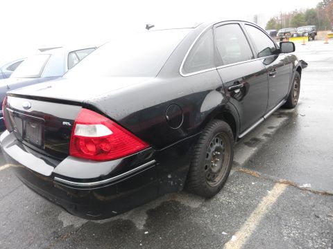 1991 Ford LTD Crown Victoria - A black sedan is parked in a lot, showing its rear end and side profile.
