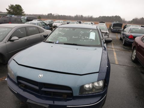1991 Ford LTD Crown Victoria - A two-tone Dodge Charger is parked in an auction lot with other vehicles under a cloudy sky.