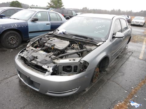 1991 Ford LTD Crown Victoria - A gray sedan sits in a lot with its hood open, missing its front passenger wheel and headlight assembly.
