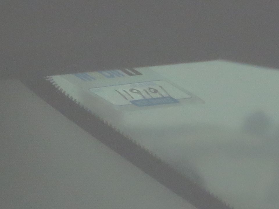 Blurry VIN/data plate visible through a windshield showing partial stamped digits.