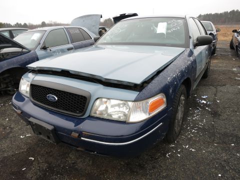 1991 Ford LTD Crown Victoria - A blue and light blue Ford Crown Victoria sits in a junkyard with its hood open.