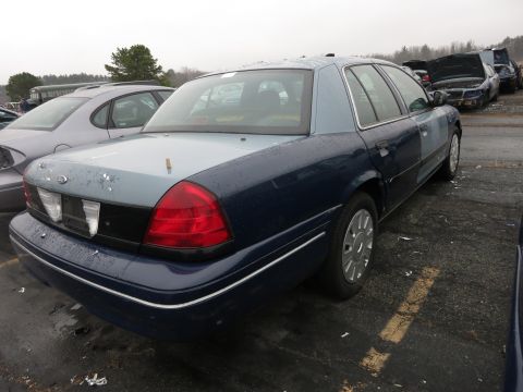 1991 Ford LTD Crown Victoria - A Ford Crown Victoria with a two-tone paint job sits in a junkyard under an overcast sky.