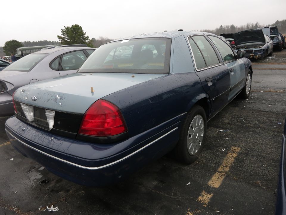 Dark blue and light blue Ford Crown Victoria, rear quarter view, showing damage and mismatched paint panels