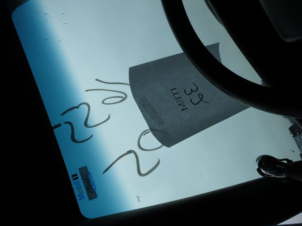 Writing on a car windshield, including numbers and a Mobil 1 sticker