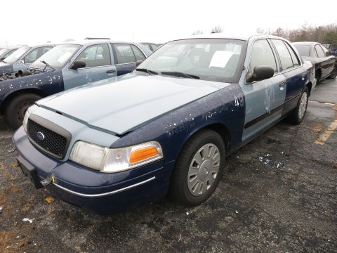 1991 Ford LTD Crown Victoria - A Ford Crown Victoria with a two-tone paint job sits in a lot with other vehicles.
