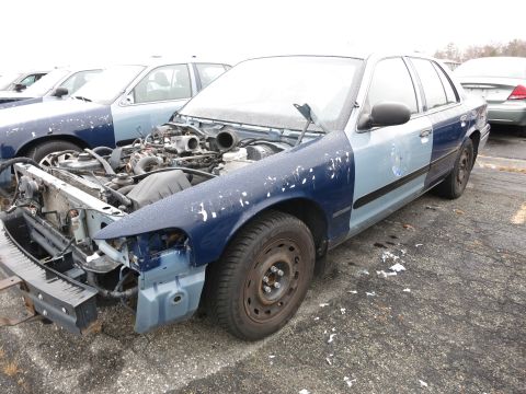 1991 Ford LTD Crown Victoria - A damaged Ford Crown Victoria sits in a lot with other vehicles, its hood open and engine compartment visible.
