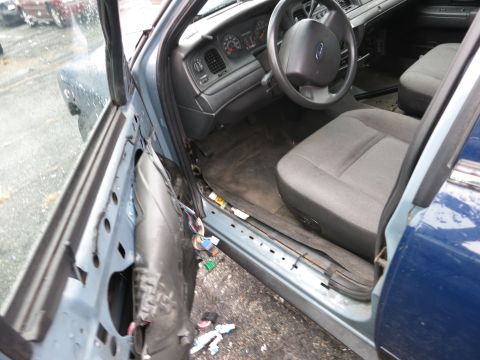 1991 Ford LTD Crown Victoria - The interior of a blue Ford Crown Victoria shows exposed wiring and a detached door panel.