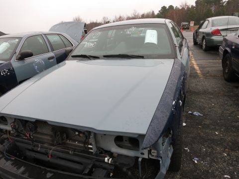 1991 Ford LTD Crown Victoria - A light blue and dark blue Ford Crown Victoria sits in a lot with other vehicles, its front end partially dismantled.
