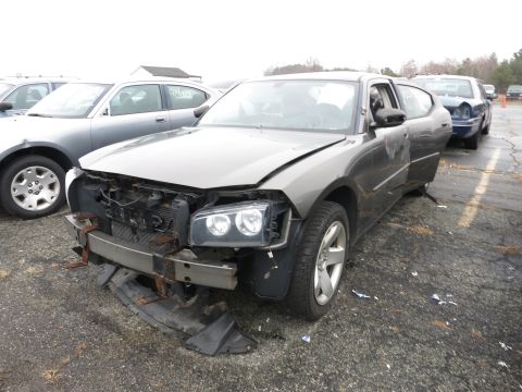 1991 Ford LTD Crown Victoria - A damaged Dodge Charger sits in a lot, showing significant front-end damage and missing parts.