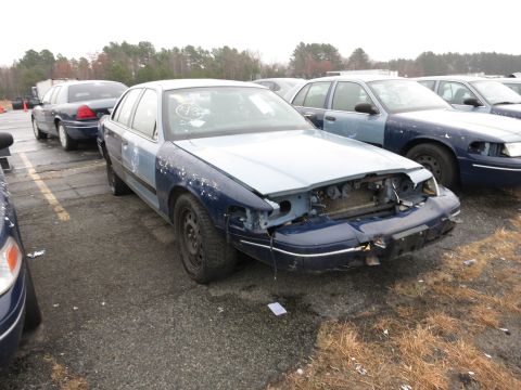1991 Ford LTD Crown Victoria - Multiple Ford Crown Victorias are seen in a lot, with the foreground vehicle showing significant front-end damage.