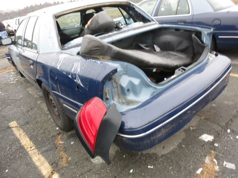 1991 Ford LTD Crown Victoria - A damaged blue 1991 Ford Crown Victoria LTD is seen from the rear quarter panel, with its taillight detached.