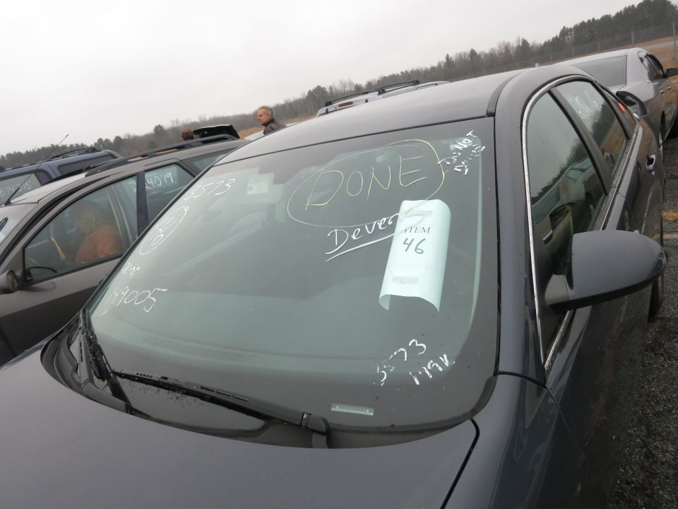Dark sedan windshield with chalk writing 'DONE' and 'Dever'. Item 46 tag attached
