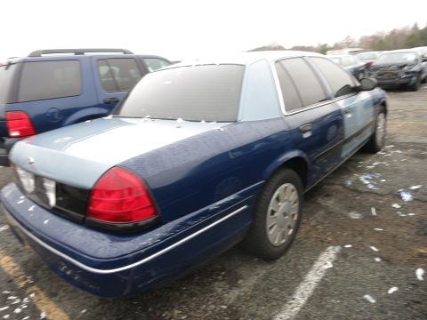 1991 Ford LTD Crown Victoria - A two-tone Ford Crown Victoria is parked in a lot next to a blue SUV.