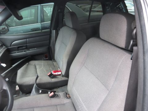 1991 Ford LTD Crown Victoria - The interior of a sedan shows worn fabric seats and a door panel. Another vehicle is visible outside.