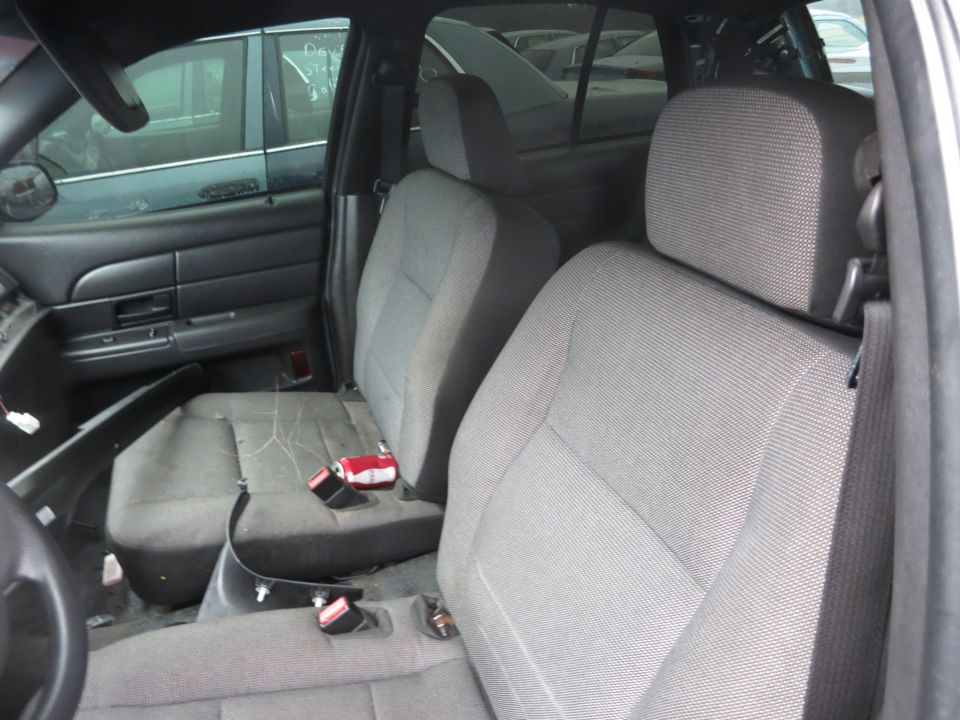 Interior of a sedan, showing front seats and door panel. Another car is visible through the window