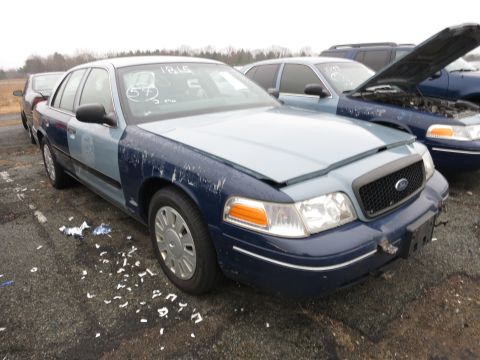 1991 Ford LTD Crown Victoria - Two Ford Crown Victorias parked in a lot, one with its hood up.