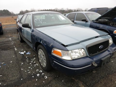 1991 Ford LTD Crown Victoria - A two-tone Ford Crown Victoria sits in a lot with other vehicles, showing signs of wear and tear.