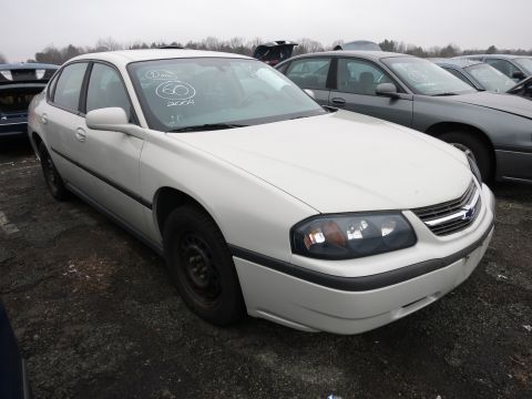 1991 Ford LTD Crown Victoria - A white sedan is parked in a junkyard with other vehicles visible in the background.