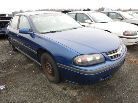 1991 Ford LTD Crown Victoria - Blue sedan with steel wheels sits in a junkyard next to other cars.