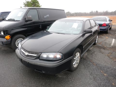 1991 Ford LTD Crown Victoria - Three vehicles are parked outdoors on a cloudy day. The main subject is a black Chevrolet Impala.