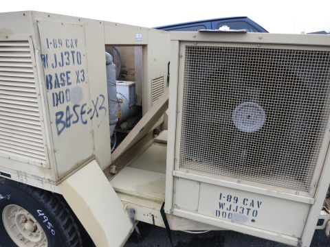 1991 Ford LTD Crown Victoria - A tan military generator unit is shown with visible stenciled markings and a large fan behind a protective grille.