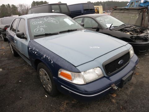 1991 Ford LTD Crown Victoria - Two-tone Ford Crown Victoria in a junkyard setting with other vehicles visible.