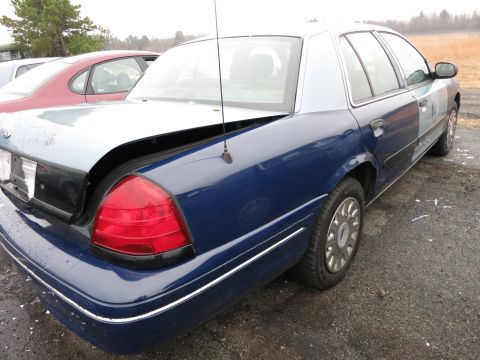 1991 Ford LTD Crown Victoria - The rear of a blue and silver 1991 Ford Crown Victoria LTD is shown with its trunk open, parked next to another vehicle.