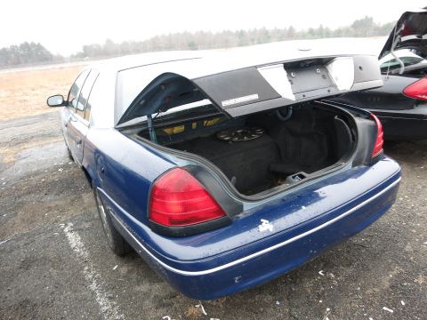 1991 Ford LTD Crown Victoria - The rear of a blue sedan is shown with its trunk open, revealing the spare tire compartment.