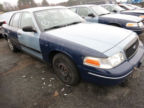 1991 Ford LTD Crown Victoria - A two-tone police car with mismatched blue fenders sits in a lot with other vehicles.
