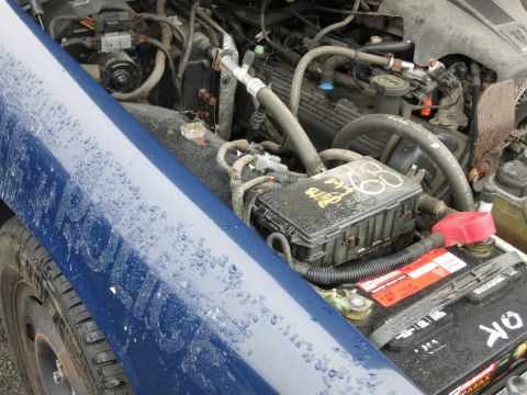 1991 Ford LTD Crown Victoria - Close-up of a blue vehicle's fender with "POLICE" text and its engine bay, showing the battery and various engine components.