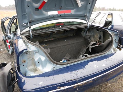 1991 Ford LTD Crown Victoria - The open trunk of a blue sedan reveals its interior, with another vehicle visible in the background.