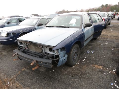 1991 Ford LTD Crown Victoria - A damaged Ford Crown Victoria wagon sits in a lot with other vehicles, its front end partially dismantled.