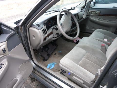 1991 Ford LTD Crown Victoria - Interior of a car with a light gray dashboard and cloth seats. A blue glove is on the carpeted floor.