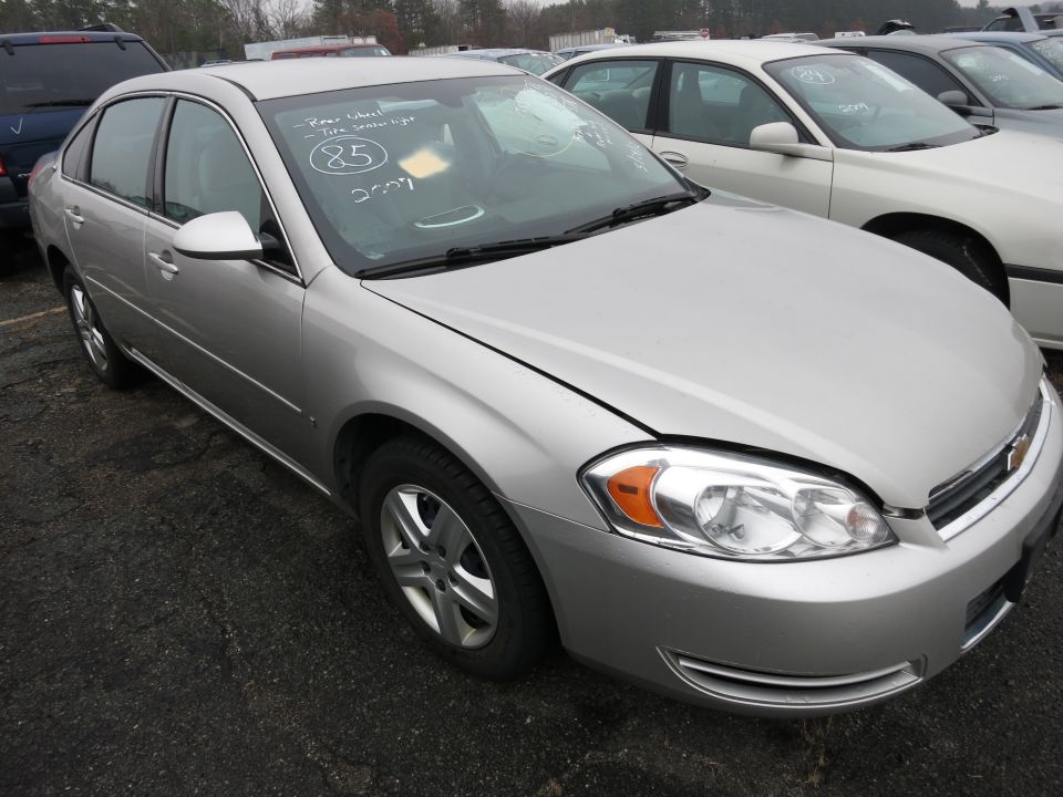 Silver sedan with handwritten notes on windshield. Other cars parked nearby
