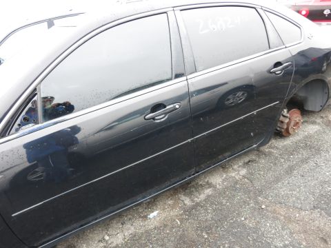 1991 Ford LTD Crown Victoria - A black sedan sits in a lot, missing a rear wheel and showing some water spots on its windows.