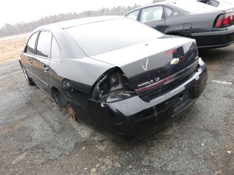 1991 Ford LTD Crown Victoria - A black sedan is parked on asphalt with another car behind it, showing damage to its rear.
