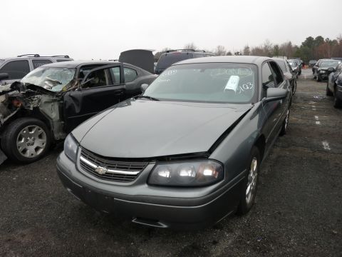 1991 Ford LTD Crown Victoria - A gray sedan sits in a junkyard with its hood open, next to a heavily damaged black car.