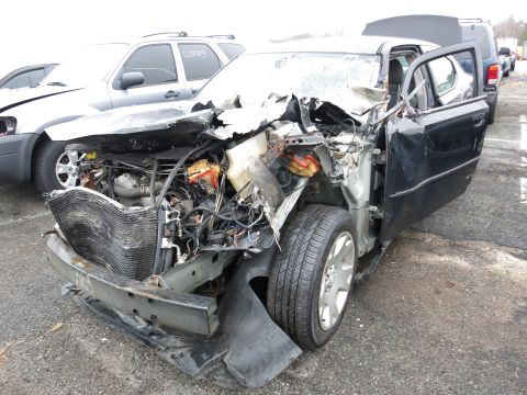 1991 Ford LTD Crown Victoria - Severely damaged black sedan with its front end destroyed and engine exposed.
