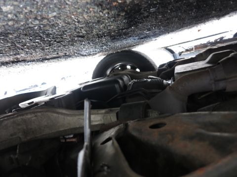 1991 Ford LTD Crown Victoria - A low-angle shot reveals the undercarriage of a vehicle, showing suspension components and a tire.