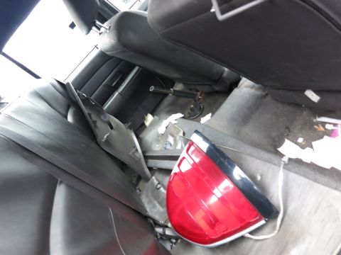 1991 Ford LTD Crown Victoria - A detached red taillight lies on the floor of a car's interior, surrounded by debris and interior panels.