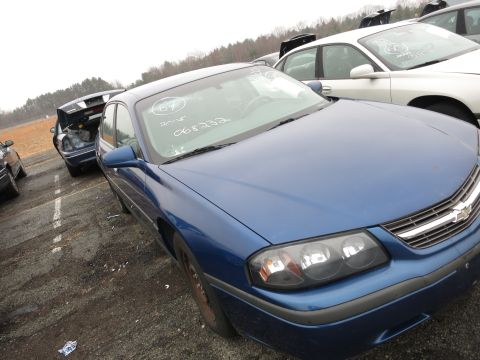 1991 Ford LTD Crown Victoria - A blue Chevrolet Impala sits in a junkyard with other vehicles visible in the background.