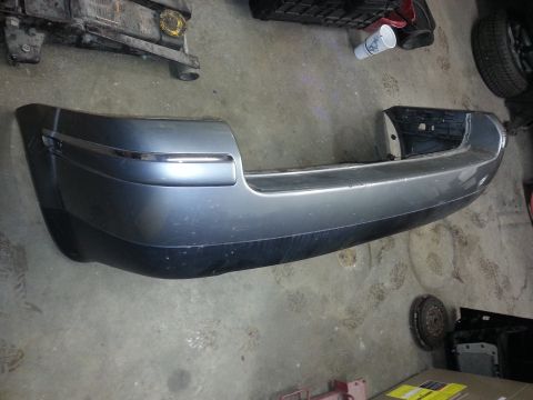 2002 Volkswagen Jetta - A detached rear bumper is shown on a workshop floor, with various car parts in the background.