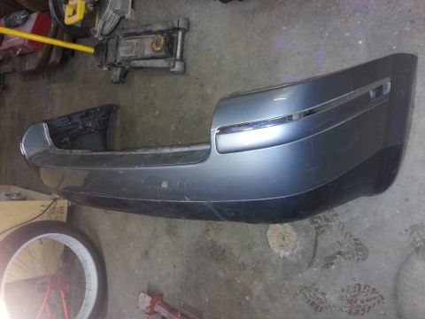 2002 Volkswagen Jetta - A detached gray rear bumper is shown on a workshop floor, with a bicycle wheel and car jack visible nearby.