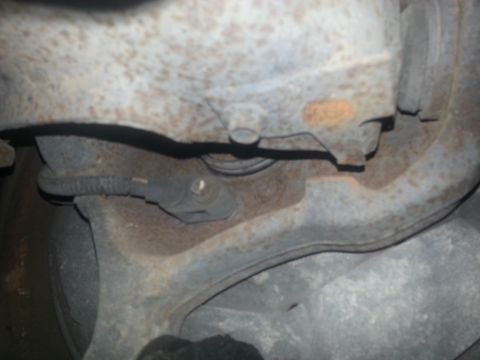 1994 Ford Bronco - Close-up view of a corroded vehicle suspension component with an electrical sensor.