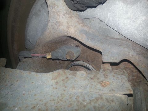 1994 Ford Bronco - Close-up view of a vehicle's brake caliper and rotor assembly, showing the sensor wire attached.