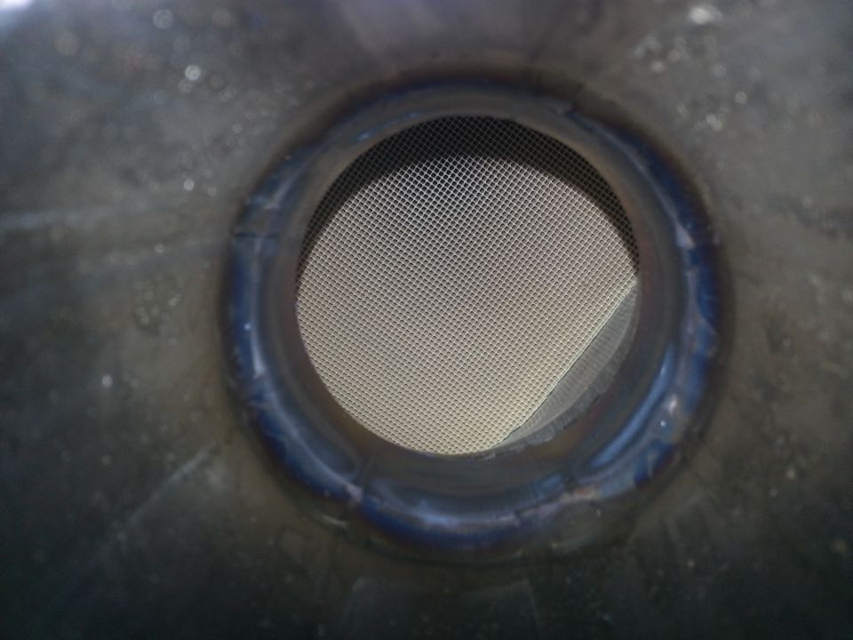 Exhaust pipe opening with a mesh screen inside. Supermotors.net logo at bottom right