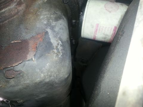 1994 Ford Bronco - A close-up view of an engine oil filter and surrounding mechanical parts, showing some rust on the undercarriage.