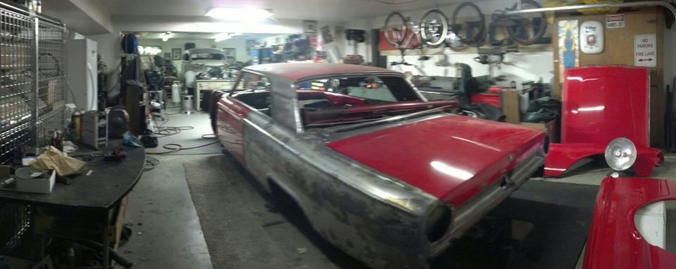 1964 Ford Fairlane body undergoing restoration in a garage, with red fenders and hood nearby