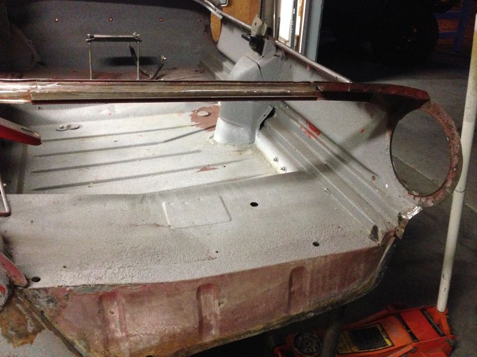 Interior floor pan of a car undergoing restoration, showing bare metal and some rust