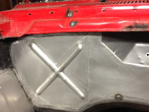 1964 Ford Fairlane - Close-up of a red car body panel showing metal reinforcement and welding work.
